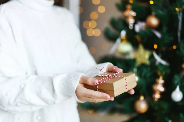 女人手里拿着圣诞礼物。光彩夺目，冷杉树背景。寒假零废物，无塑料 — 图库照片