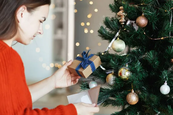 女人在圣诞树旁边打开礼品盒，看贺卡。圣诞时间，新年假期 — 图库照片