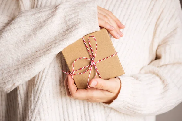 穿着舒适的米色针织毛衣的女人送给圣诞节礼物盒红色缎带。情人节和母亲节礼物的概念 — 图库照片
