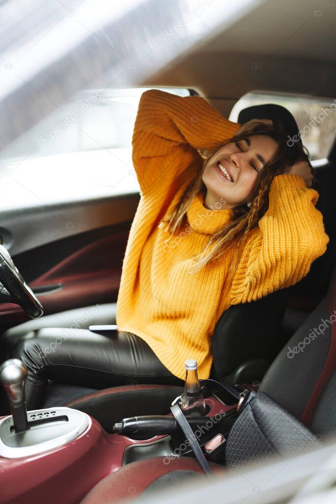 Beautiful young woman laughing in the car glad positive expression, being satisfied with unforgettable journey by car, sits on drivers seat, enjoys music. People, driving, transport concept