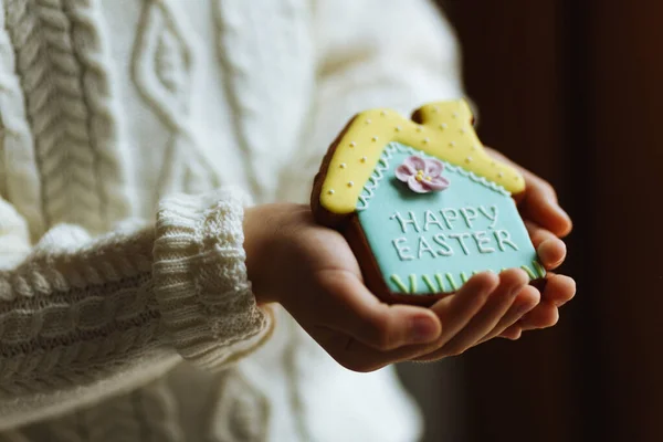 Мальчик держит пряничное печенье в форме дома с надписью Счастливой Пасхи — стоковое фото