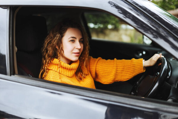 Портрет молодой красивой женщины в желтом свитере, сидящей в машине