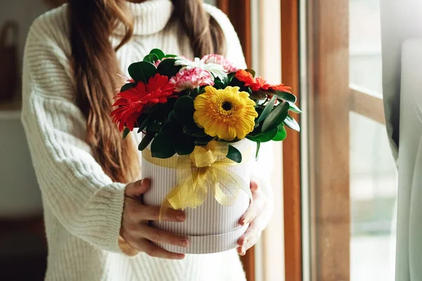 Woman in white sweater holding flowers bouquet in hands against home lifestyle interior. Holiday celebration festive floral concept — Stock Photo, Image