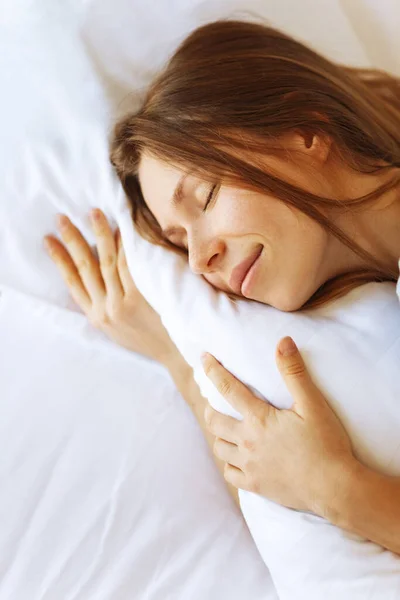 Portré fiatal nő élvezi alvás idő az ágyban, közelről, emelkedett kilátás, ölelés párna — Stock Fotó