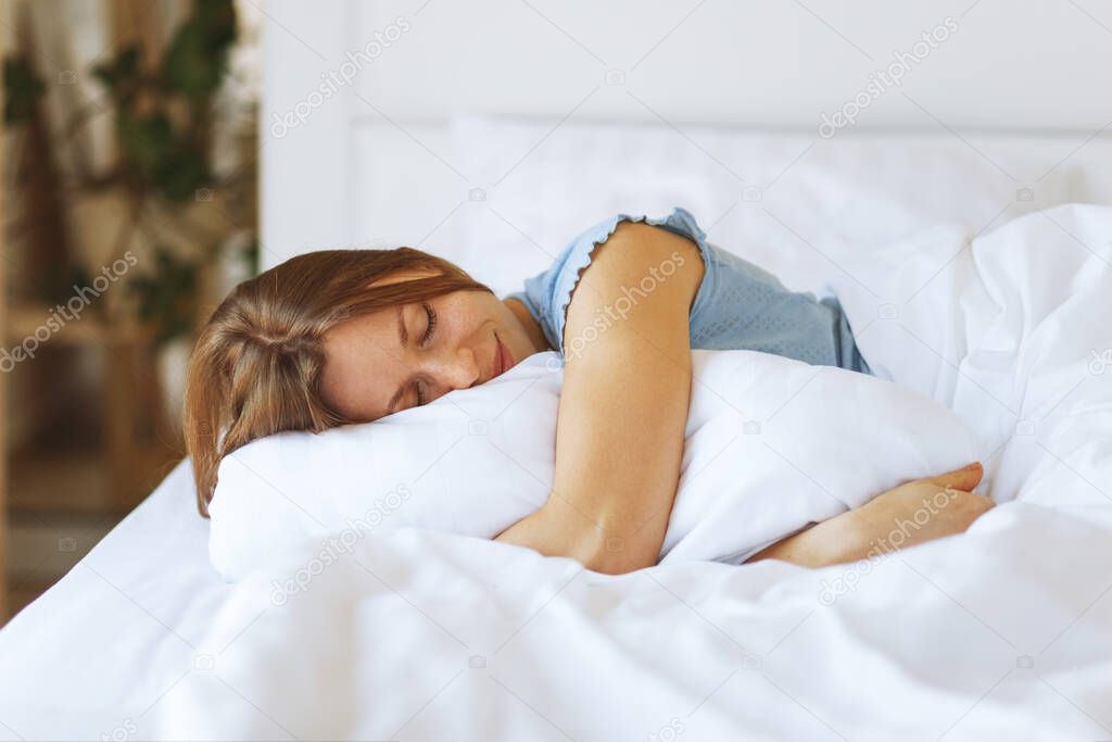 Portrait of young woman enjoying sleeping time in bed , close up ,elevated view, hugging pillow
