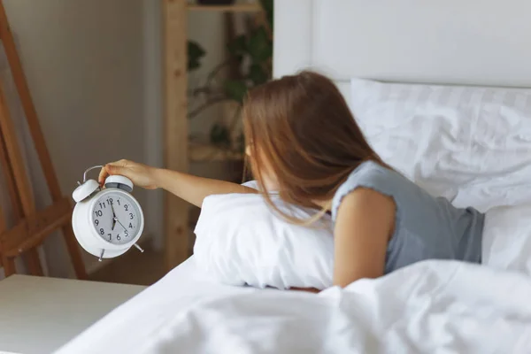 Egy nő alszik az ágyon, kikapcsolja az ébresztőórát, reggel felébred, szelektív fókusz. — Stock Fotó