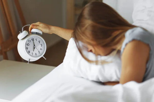 Egy nő alszik az ágyon, kikapcsolja az ébresztőórát, reggel felébred, szelektív fókusz. — Stock Fotó