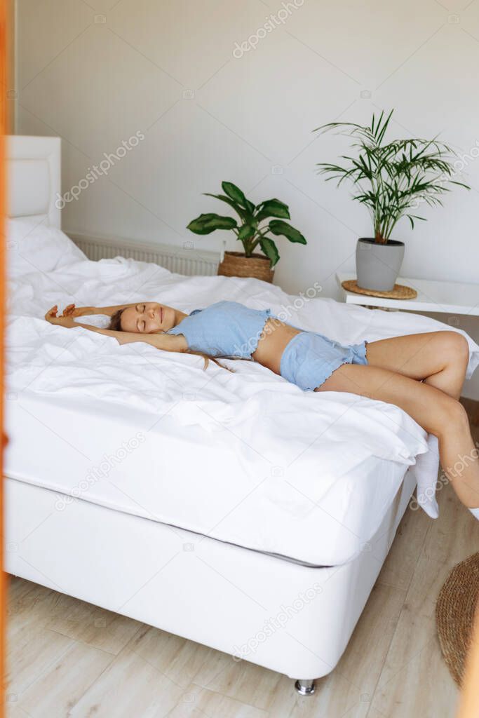 Young woman in sleepwear laying on bed,stretching after sleeping,morning vibes