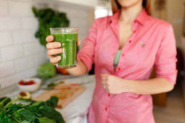 Unrecognizable female holding glass of green spinach detox smoothie