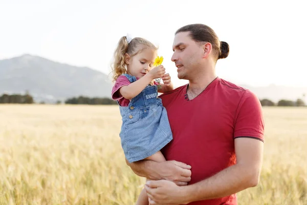 Father playing and carrying his daughter on hands.Mature man playing with his little daughter in nature.Dad playing with daughter in park and hugging her.