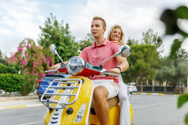 Happy couple in love riding a motorbike on summer city streets ,man and woman travel . Young riders enjoying themselves on trip. Adventure and vacations concept.