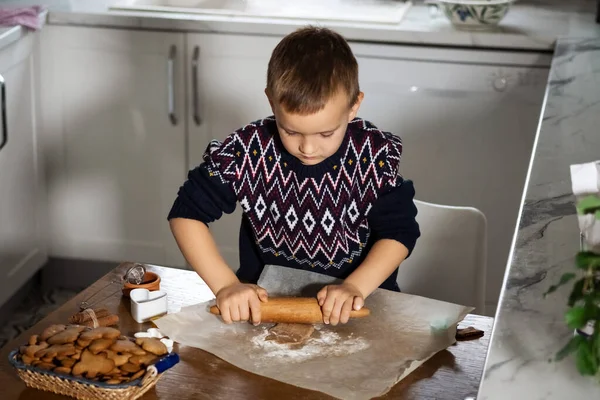 A boy prepares gingerbread cookies in the kitchen. Christmas family traditions. Leisure of the child during the New Year holidays. Top view