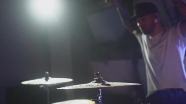 Davulcu davul tokmağı ile ıslak davul ziline vurur ve su yavaş çekimde sıçrar. Müzik aletlerinin kayıt stüdyosunda