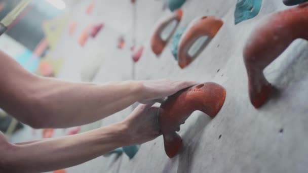 Sporty girl rock climber climbs the climbing wall. Uses a safety rope and climbing clothing. Grabs hands on stones and ledges — Stock Video