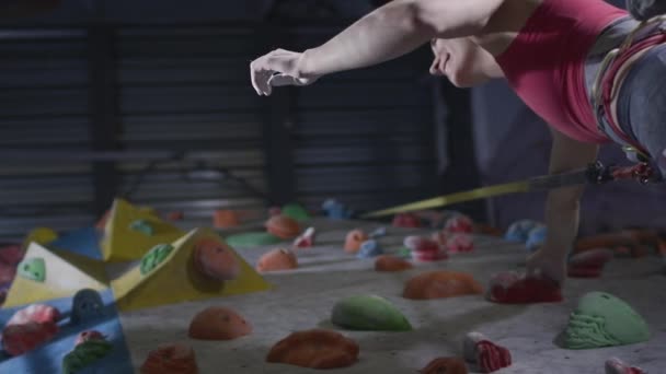 Sport girl and athletic man climbers give five on the climbing wall in the gym. Uses a safety rope and clothing on the bouldering wall — Stock Video