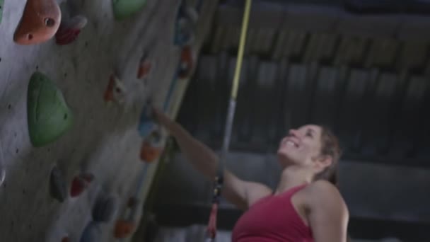 Sport flicka och atletisk man klättrare ger fem på klätterväggen i gymmet. Använder ett säkerhetslina och kläder på boulderingväggen — Stockvideo