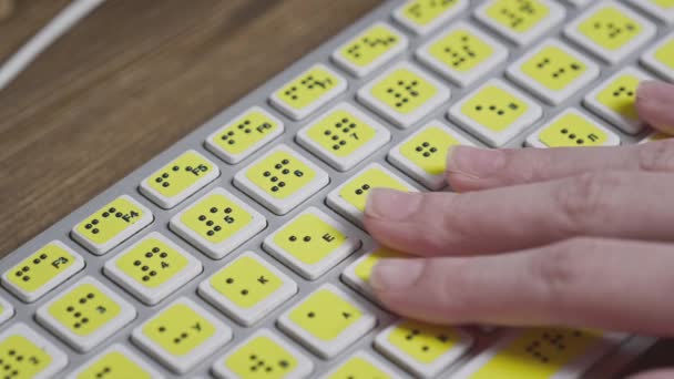 Primer plano de un teclado de ordenador con braille. Una chica ciega está escribiendo palabras en los botones con sus manos. Dispositivo tecnológico para personas con discapacidad visual — Vídeo de stock
