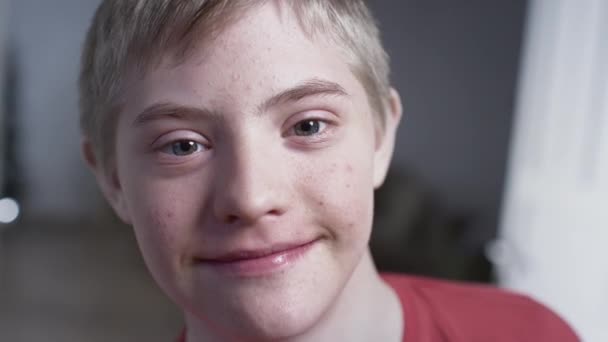 Ritratto di un bambino con sindrome di Down. L'adolescente sorride, guarda nella telecamera. Disabili a casa. Vita con disabilità — Video Stock