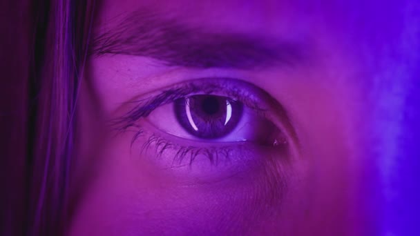 Extreme close-up Beautiful girl opens one eye, neon pink blue light. Attractive feminine look. Party nightclub, fashion show. Macro slow motion — Stock Video
