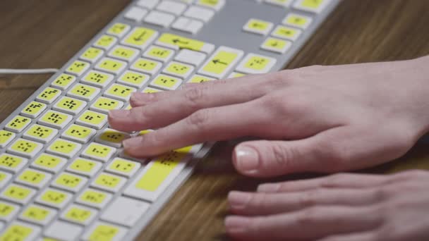 Nahaufnahme einer Computertastatur mit Brailleschrift. Ein blindes Mädchen tippt mit den Händen Wörter auf die Knöpfe. Technisches Gerät für sehbehinderte Menschen — Stockvideo