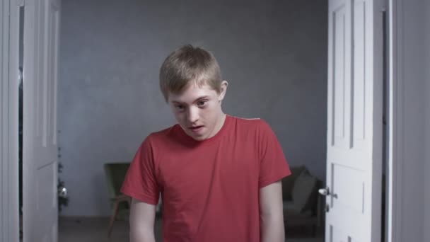 Portrait of a child boy with down syndrome. The teenager smiles, looks into the camera. Disabled person at home. Life with a disability — Stock Video