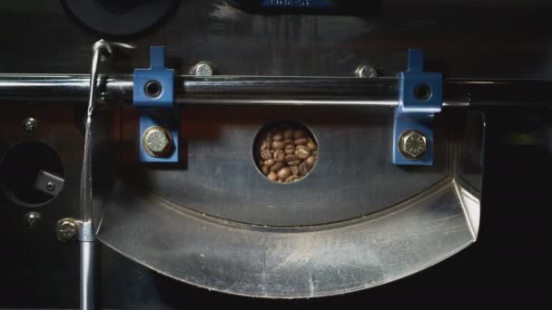 Οι κόκκοι του καφέ στριφογυρίζουν σε μια μηχανή. Ψήνω κόκκους καφέ σε εξοπλισμό ψησίματος. Φρεσκοψημένοι κόκκοι καφέ από μια μεγάλη καφετιέρα — Αρχείο Βίντεο