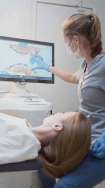 Dişçi kız, dokunmatik monitörde 3 boyutlu diş modeli gösteriyor. Klinikte diş muayenesi, teşhis