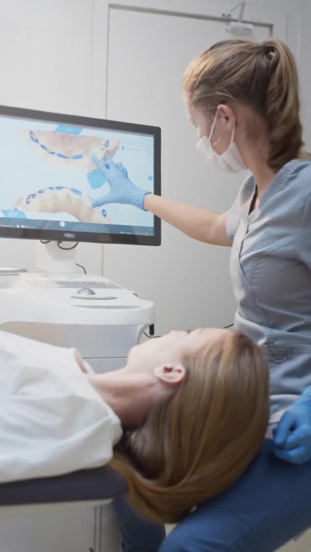 Lekarz dentysta pokazuje model 3D zębów na monitorze dotykowym. Konsultacja stomatologiczna w klinice, diagnostyka — Wideo stockowe