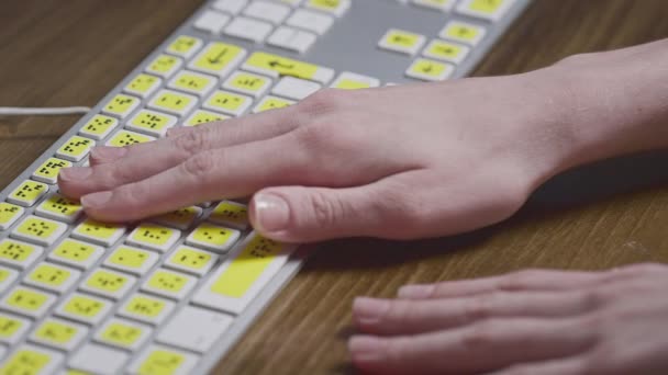 Nahaufnahme einer Computertastatur mit Brailleschrift. Ein blindes Mädchen tippt mit den Händen Wörter auf die Knöpfe. Technisches Gerät für sehbehinderte Menschen — Stockvideo