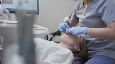 Doktor klinikteki hastaların dişlerini tarıyor. Diş hekimi elinde çene ve ağız için bir 3D tarayıcı tutuyor. Diş sağlığı. Tıbbi monitörde 3 boyutlu diş eti ve diş eti modeli oluşturur
