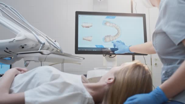 Meisje arts tandarts demonstreert een 3D-model van tanden op een touch monitor. Tandheelkundig consult in de kliniek, diagnostiek — Stockvideo