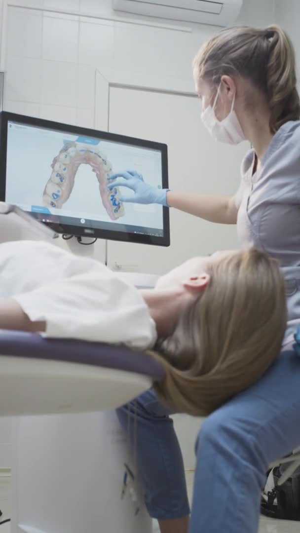 Dokter gigi wanita menunjukkan model 3D gigi pada monitor sentuhan. Konsultasi gigi di klinik, diagnosa — Stok Video