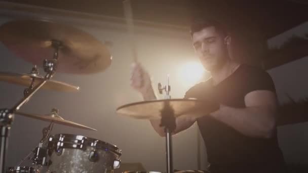 Ein junger attraktiver männlicher Schlagzeuger spielt mit einem Stock auf einem Schlagzeug. Macht Schläge auf metallene Becken. Home-Probenstudio für Ton- und Liedaufnahmen. — Stockvideo