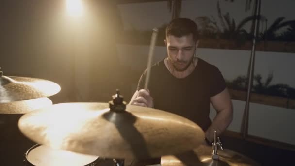 Ein junger attraktiver männlicher Schlagzeuger spielt mit einem Stock auf einem Schlagzeug. Macht Schläge auf metallene Becken. Home-Probenstudio für Ton- und Liedaufnahmen. — Stockvideo