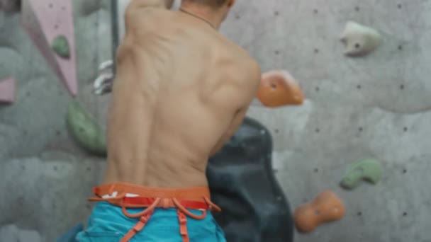 Athletic male climber quickly climbs an artificial climbing wall. Speed lift. A strong experienced rock climber practices boulder wall climbing inside — Stock Video