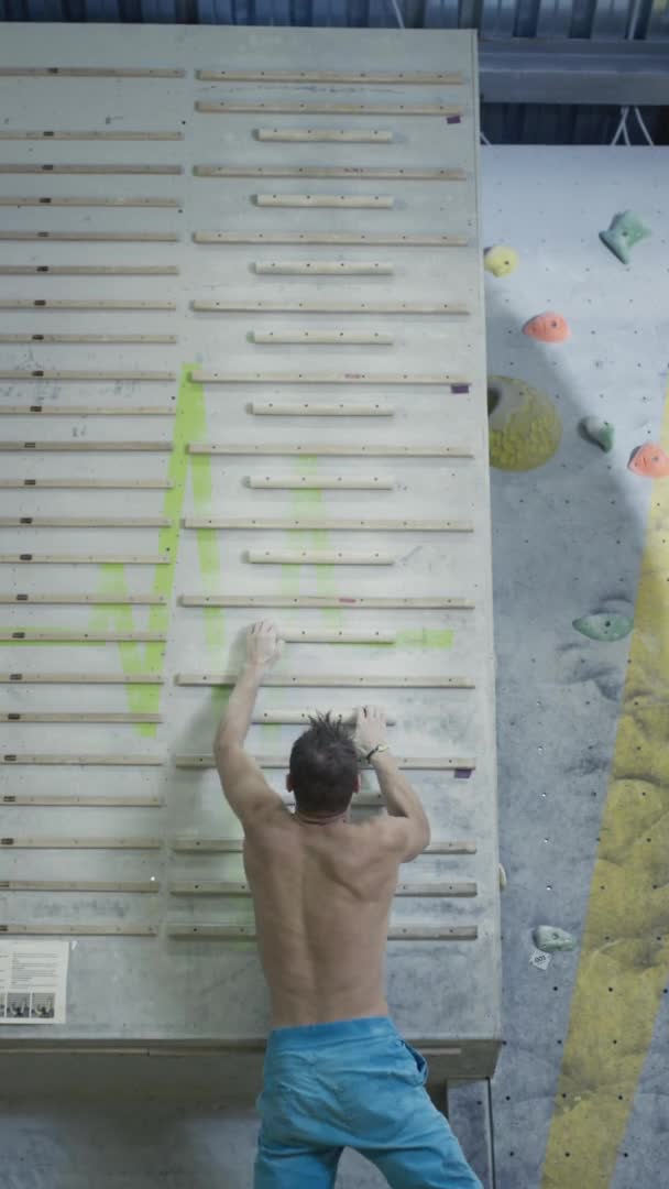Egy atlétikai ember megmászik egy fogólapot, hogy sziklamászást szimuláljon. Aktív életmód, extrém sport sziklázás. Mászóberendezés ujjgyakorlat céljára — Stock videók