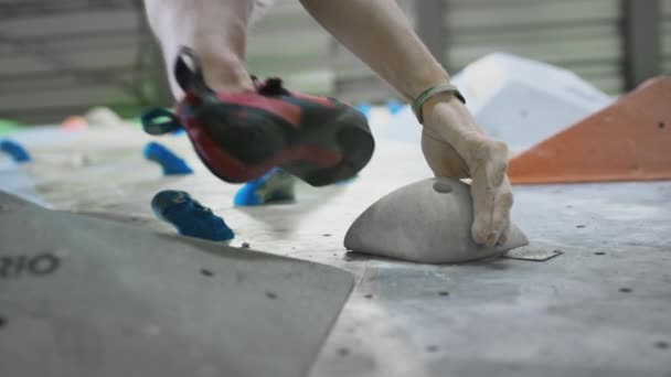 Bottom view: A sporty Caucasian man climbs a bouldering wall. Moves legs on ledges. Practices climbing on an artificial indoor wall. Extreme sports — Stock Video