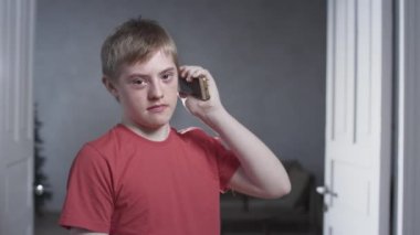 Down sendromlu bir çocuğun portresi. Çocuk bir akıllı telefonu eliyle tutuyor, telefonla konuşuyordu. Bir çocukta kromozom genetik bozukluk.