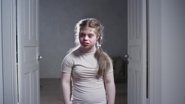 Potret seorang gadis dengan Down Syndrome. Bayi tersenyum dengan gembira dan melihat ke kamera di rumah. Pendidikan rumah tangga dan rehabilitasi — Stok Video