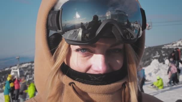 Retrato: linda menina snowboarder com capuz e máscara de céu ou óculos. Brincadeira olhando para a câmera, desfrutando de resort de inverno e aventura de viagem. — Vídeo de Stock