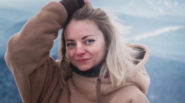 Güzel bir kızın portresi kışın saçını düzeltir. Güzel Mavi Gözler, Sarı Saçlar 'da esen Rüzgar. İyi kayaklar. Kapüşon giymişti.