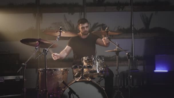 Um tipo bonito a tocar bateria num estúdio de gravação. A fazer música de um artista independente. Estilo rock na escola da criatividade. Rocker toca sozinho — Vídeo de Stock