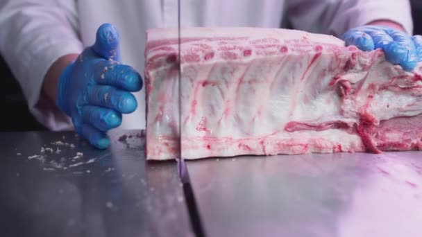 Procesamiento industrial de carne. Un cocinero corta un trozo de lomo en una carnicería en una máquina con una sierra de cinta. Ribeye o carne de vacuno de mármol. — Vídeos de Stock