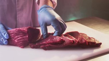 Aşçı bir adam kasapta taze kırmızı fileto kesiyor mutfak bıçağıyla. Pirzola ya da mermer et dilimleri.