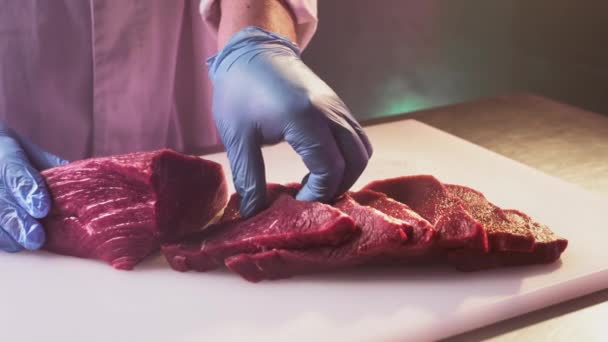 Ένας μάγειρας κόβει ένα φρέσκο κόκκινο ωμό φιλέτο σε ένα κρεοπωλείο με κουζινομάχαιρο. Ψιλοκομμένο κρέας premium ribeye ή μαρμαροειδές βόειο κρέας. — Αρχείο Βίντεο