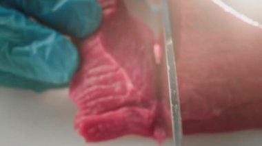 Aşçı bir adam kasapta taze kırmızı fileto kesiyor mutfak bıçağıyla. Pirzola ya da mermer et dilimleri. Makro çekim