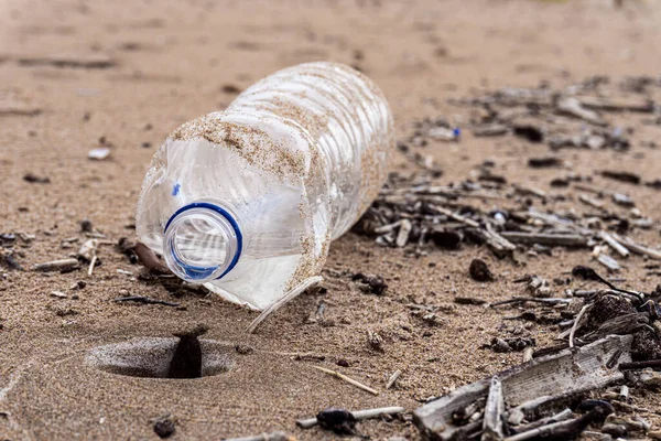 一个塑料瓶的特写被扔进了肮脏的沙子里海滩垃圾的概念 — 图库照片