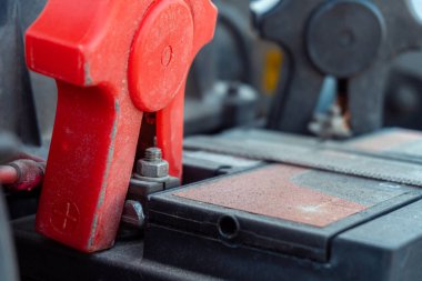 Tozlu eski bir araba aküsünün uçlarına bağlı başlangıç kıskaçlarının seçici odak noktası ile yakın plan. 