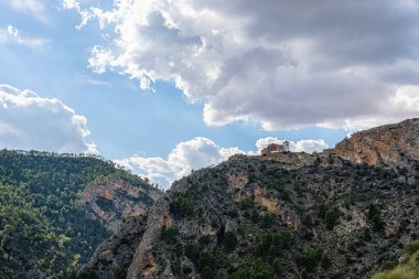 Dağlık arazi, dağın tepesinde El Cristo de la Vida 'nın mabedi, güneş ve bulutlarla kaplı mavi gökyüzü. Villa de Ves, Albacete (İspanya).