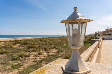 Sahil kenarındaki bir evin dış duvarındaki dekoratif bir sokak lambasının seçici odağı ile yakın plan.